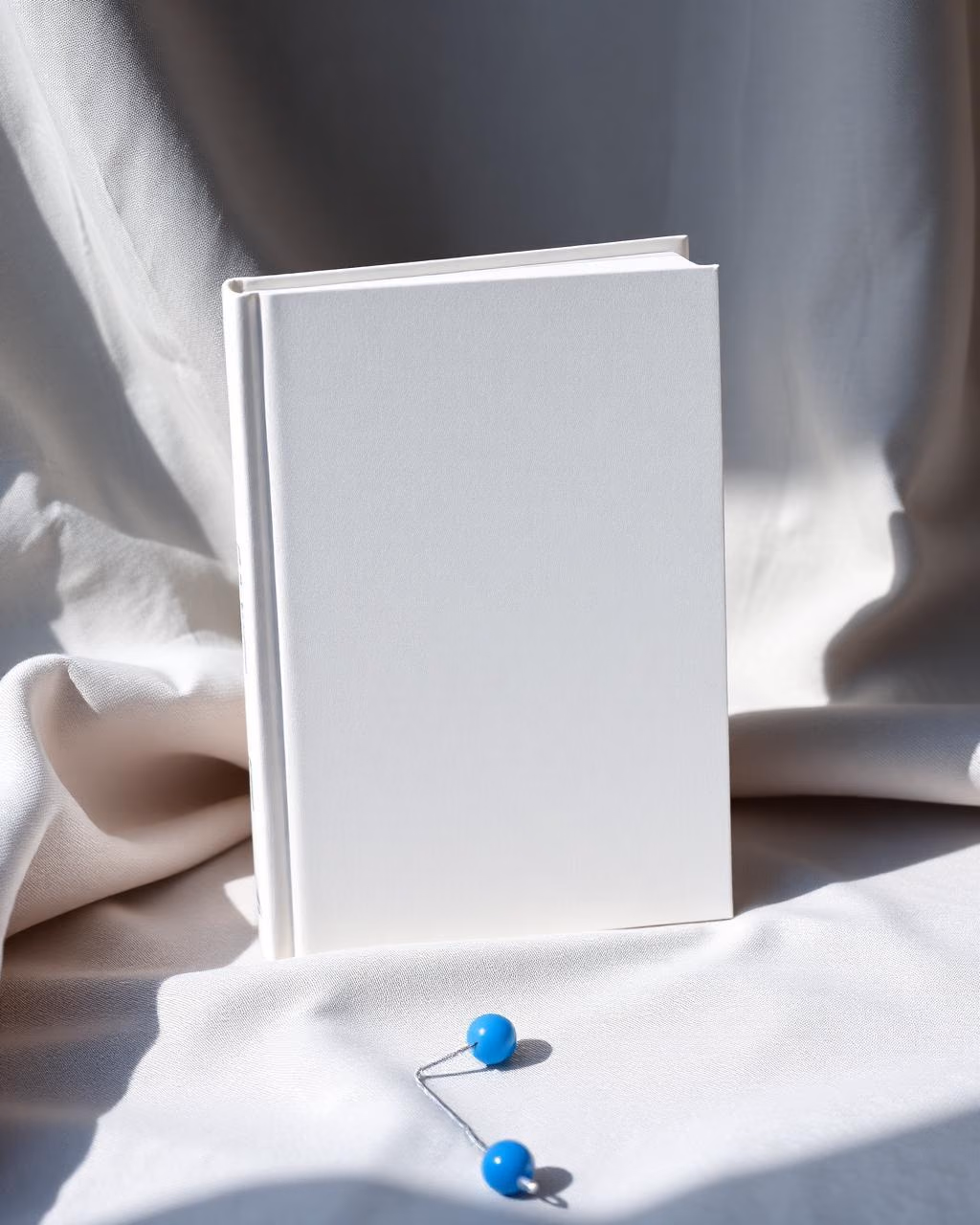 Fotografia provisória de um livro de capa dura em branco sobre tecido claro.
