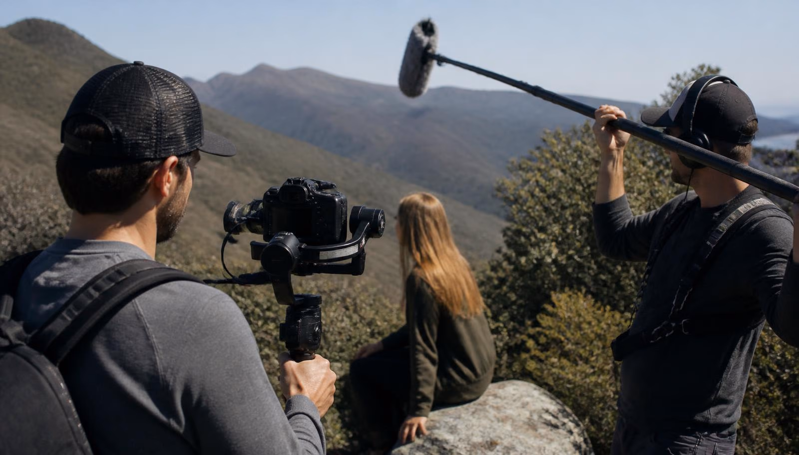 Equipe de produção audiovisual gravando ao ar livre com câmera e microfone boom.